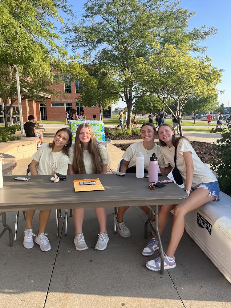 Student council members Abby Butterfield, 12th, Georgie Shere, 12th, Kamryn Exner, 12th, and Morgan Blair, 11th, get ready to welcome students to Street Fest.