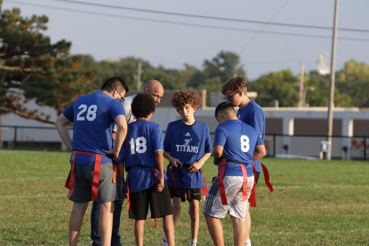 Mr. Cain, Unified Sports sponsor and coach, leads a huddle with the Unified Flag Football team.