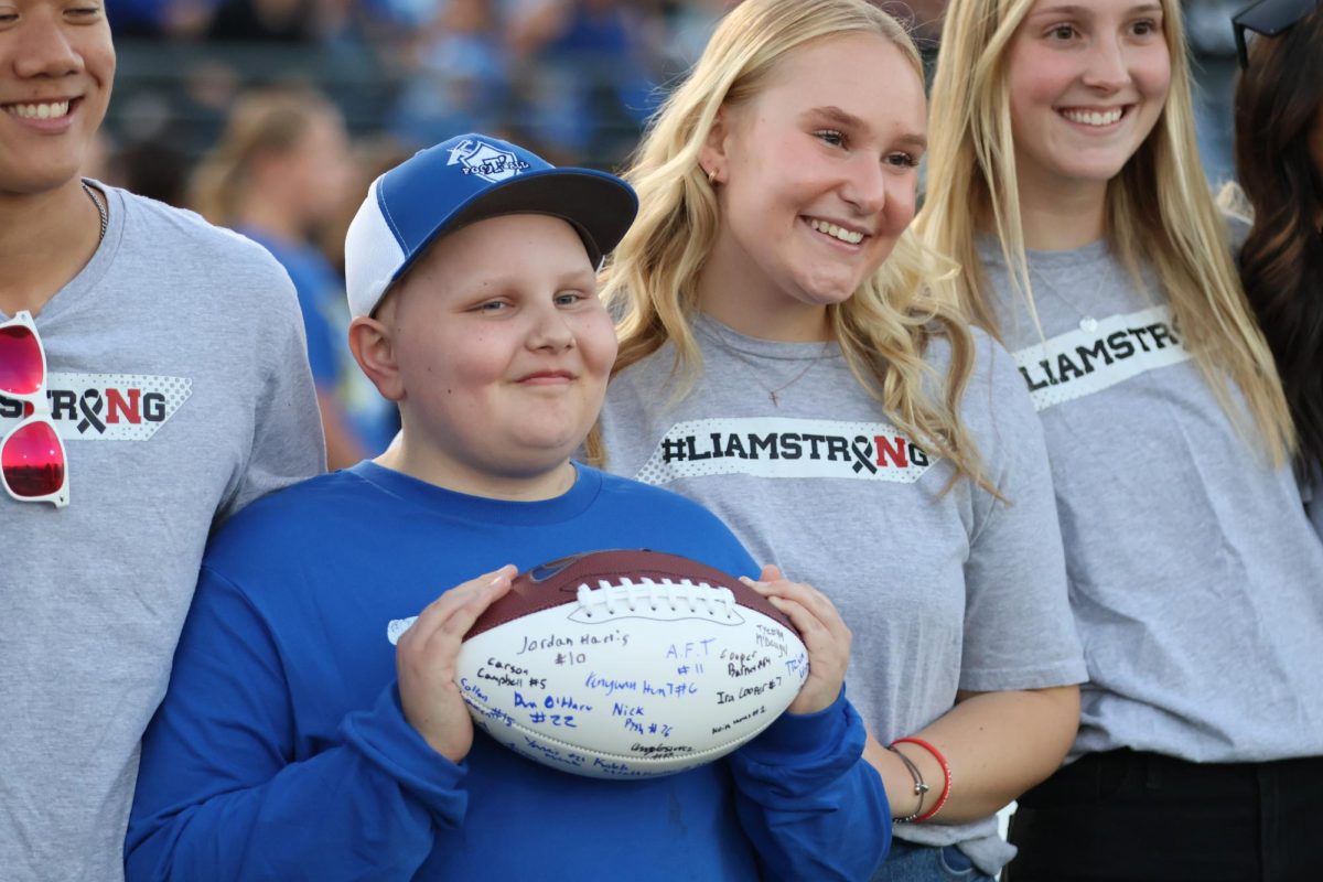 Liam Settles with sister Halle, holding signed football from team. (photo Kaiya Sharpe)