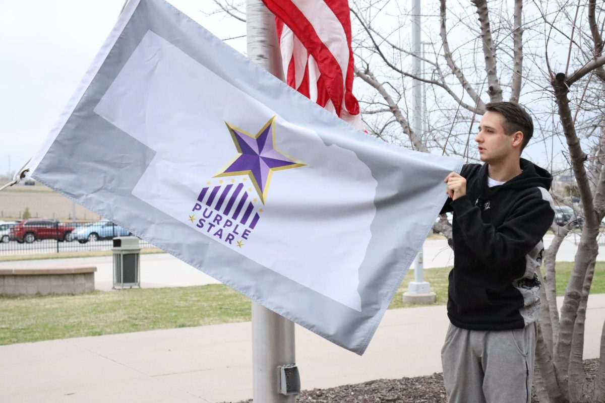 Brandyn Greenwell, 11th, Hanging Purple Star flag in front of the school