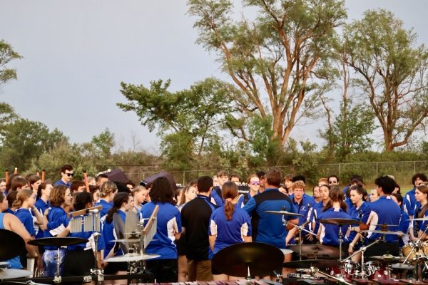 The Titan Band circles up after community night, raising their voices in the Strength and Honor chant before proudly naming the clarinet section Best Section.