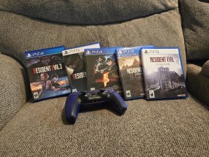 Personal copies of various Resident Evil games, including Resident Evil 3: Remake, Resident Evil 4: Remake, Resident Evil 5, Resident Evil 7: Biohazard, and Resident Evil 9: Requiem. They're positioned on the couch, with a PS5 remote in front of them.